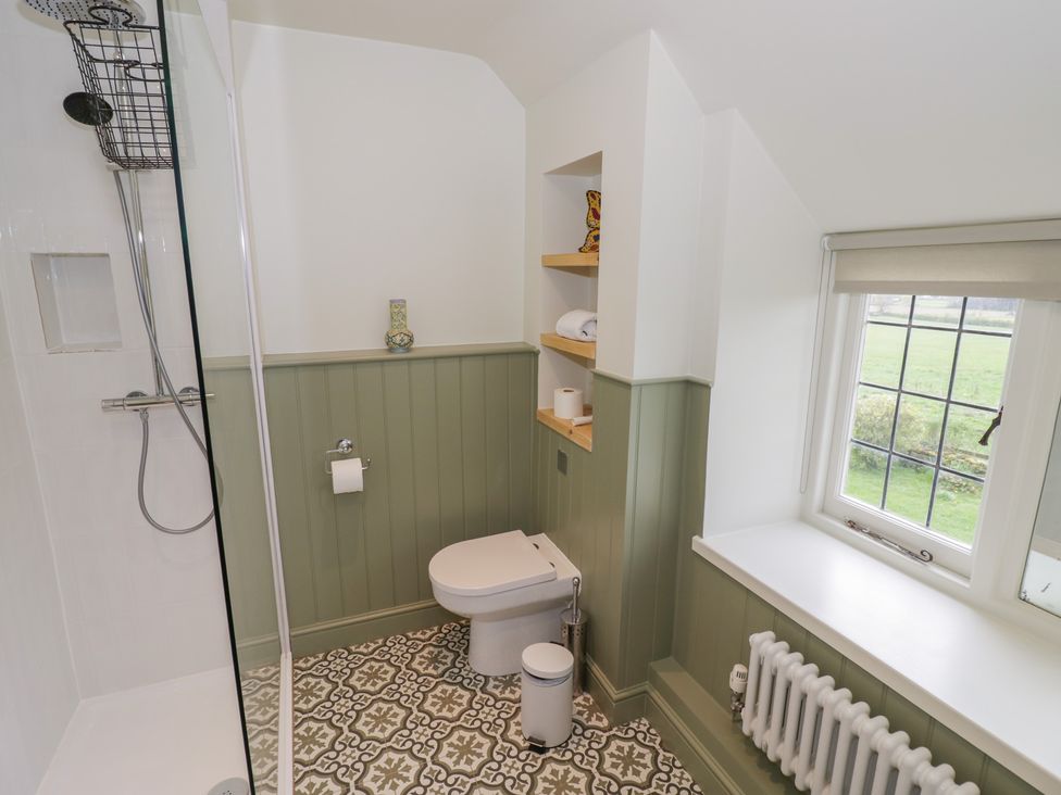 A bathroom with a shower, toilet and shelves at Priors Mead in Claydon near Cropredy