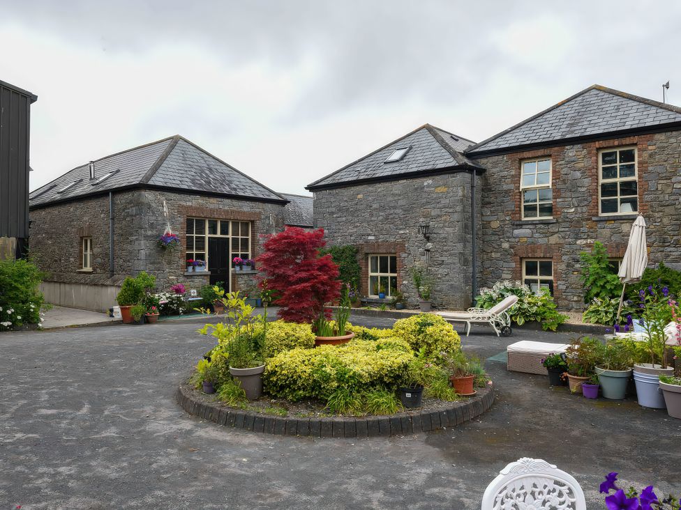 A courtyard with buildings and flower arrangements at Coach House in Kilbeg near Borris-In-Ossory, County Laois
