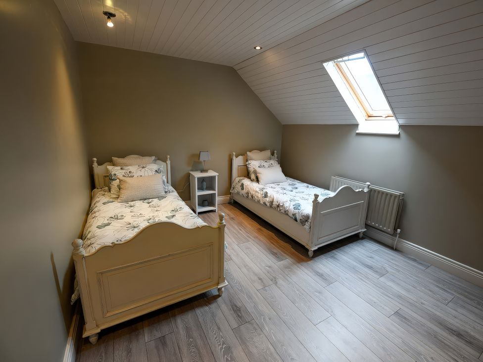 A bedroom with two beds and a bedside table at Coach House Kilbeg near Borris-In-Ossory, County Laois