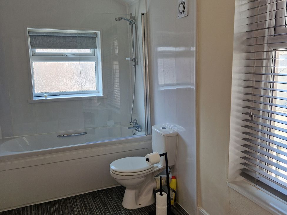 A bathroom with a bathtub, toilet, and shower at 18 Howard Street, Scarborough