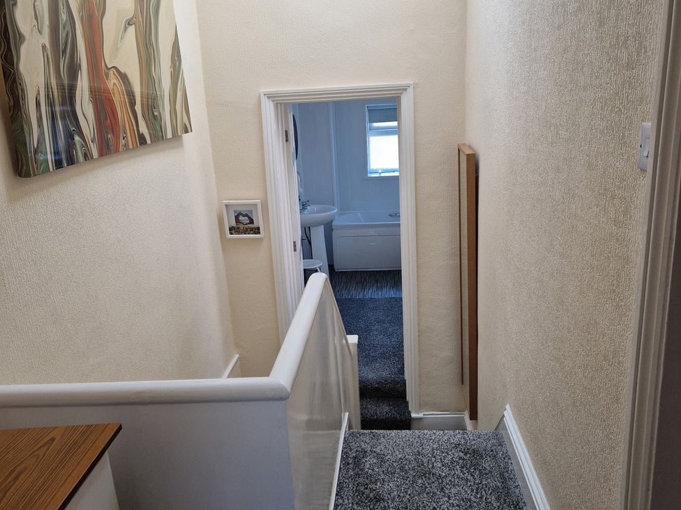 A hallway with a staircase and a doorway leading to a bathroom at 18 Howard Street Scarborough