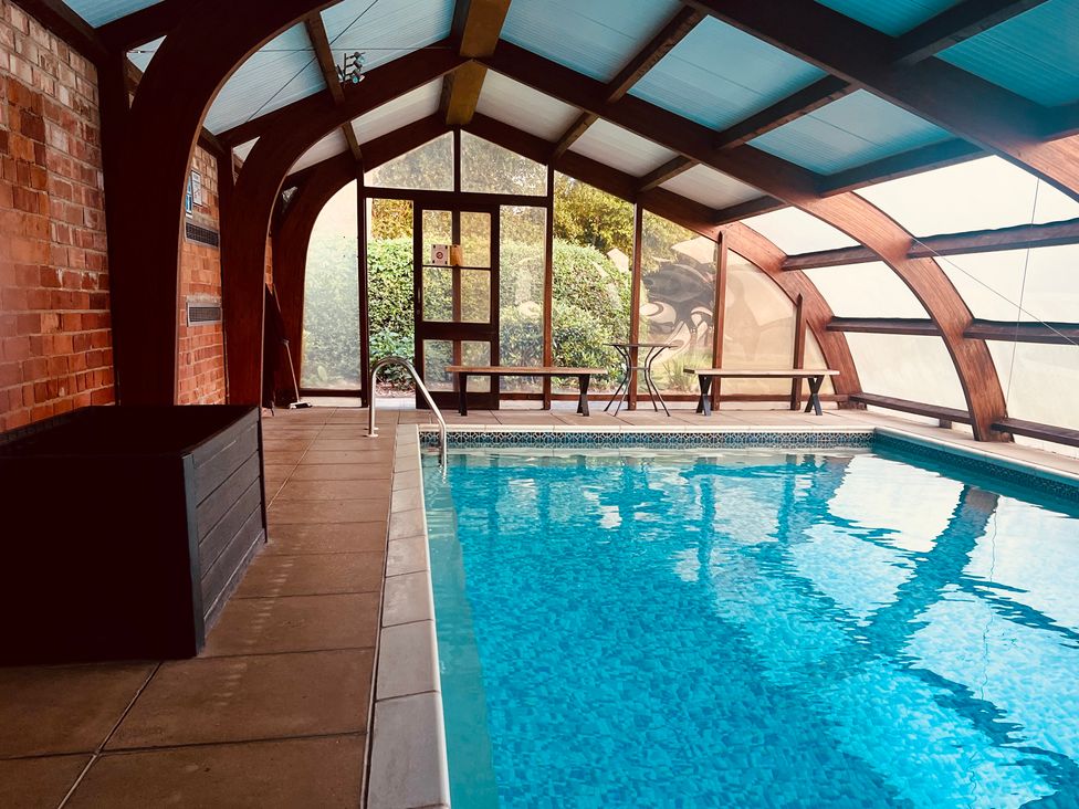 An indoor pool with benches and large windows at Moortown House in Caistor