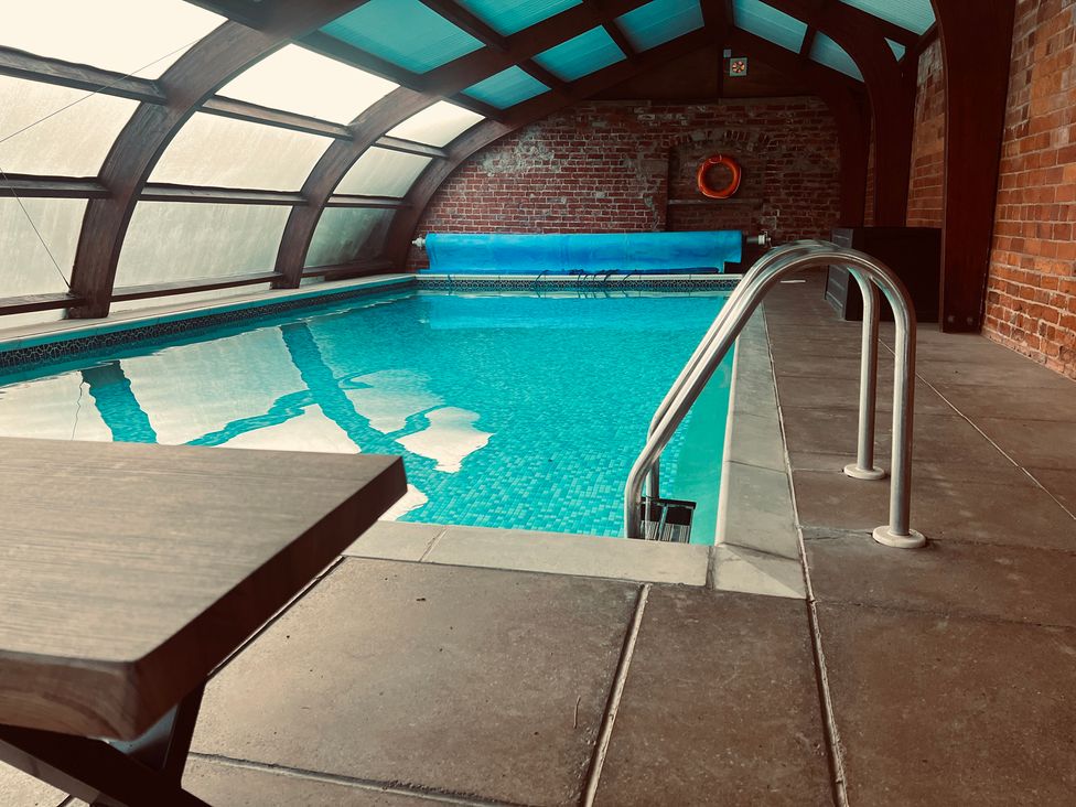 An indoor swimming pool with a table and life ring at Moortown House in Caistor