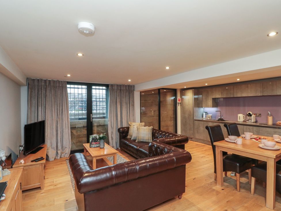 A living room with a sofa, coffee table, and kitchen at Tornado @ Engine Shed Whitby