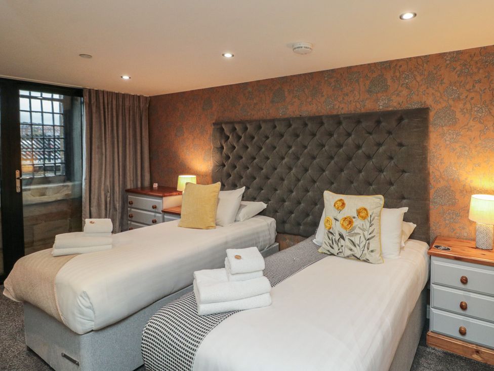 A bedroom with two beds and a bedside table at Tornado @ Engine Shed in Whitby