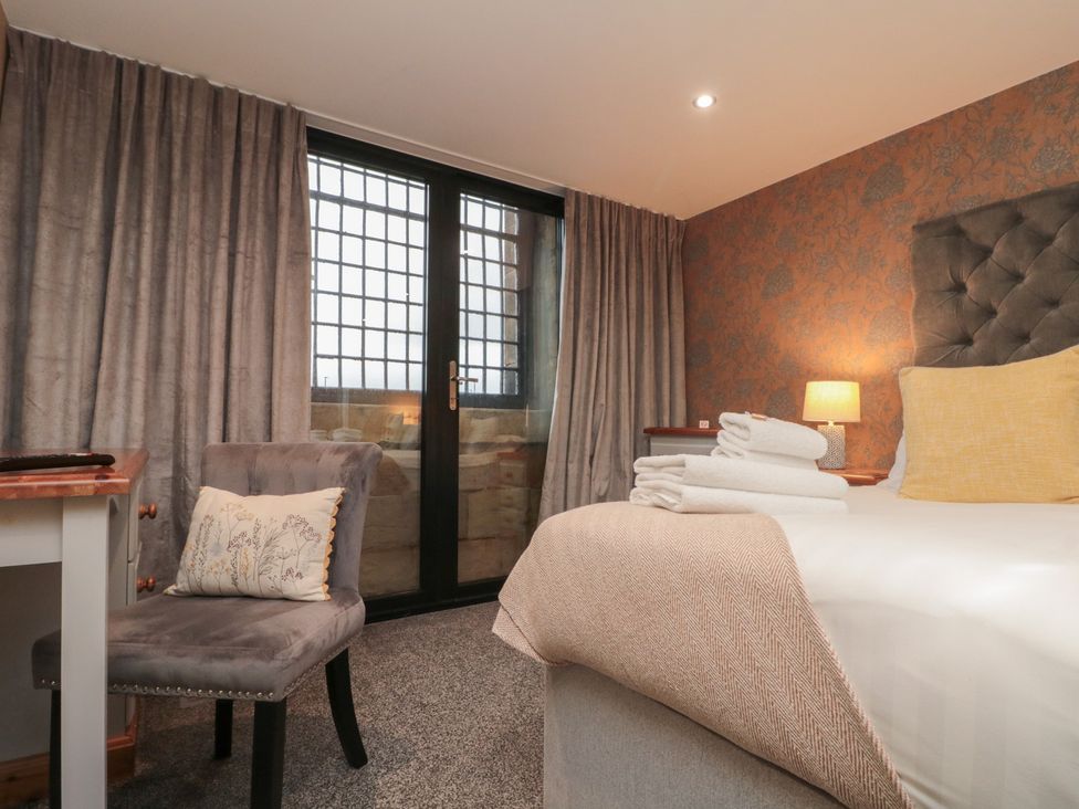 A bedroom with a bed, towels, and a chair at Tornado @ Engine Shed Whitby