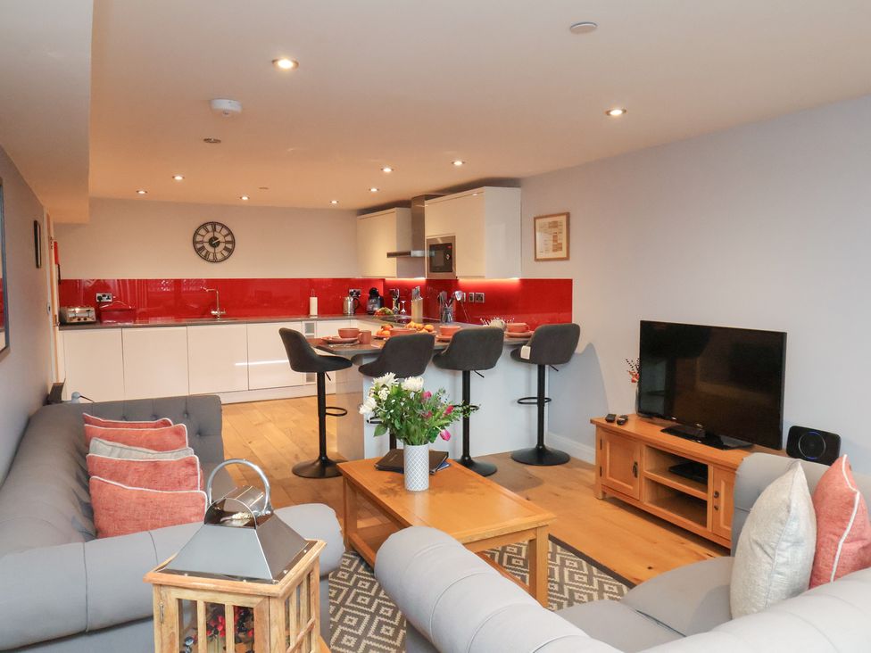 A living room with a kitchen and bar stools at Olton Hall @ Engine Shed in Whitby