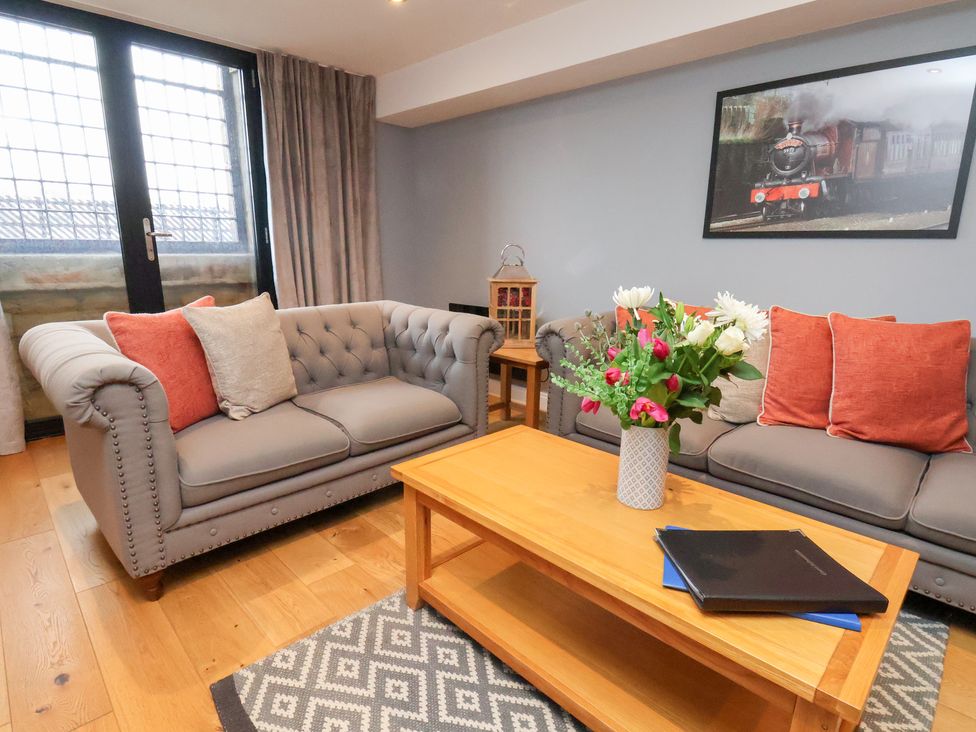 A living room with a sofa, table, and floral arrangement at Olton Hall @ Engine Shed, Whitby