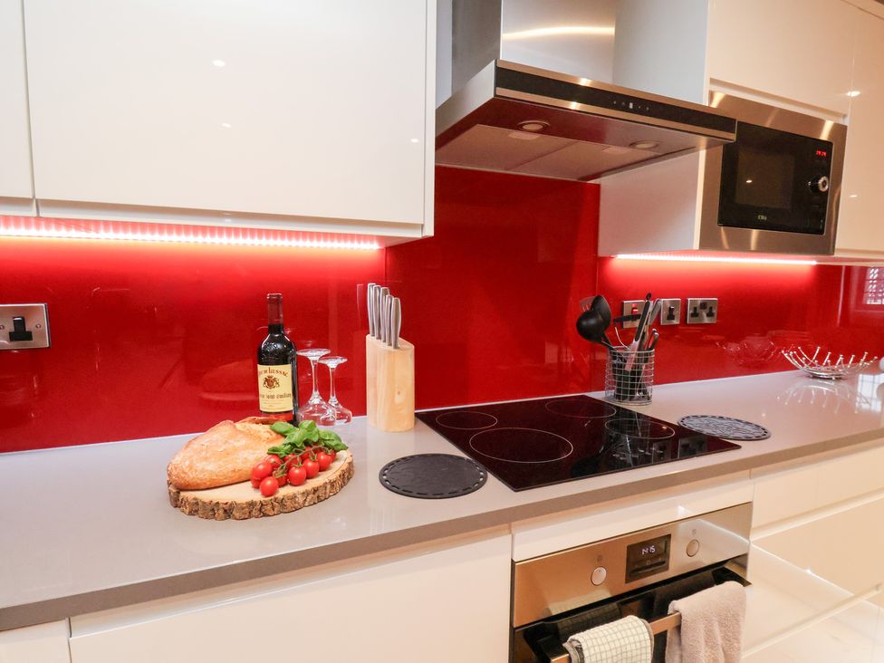 A kitchen with a countertop featuring bread, wine, and utensils at Olton Hall @ Engine Shed in Whitby