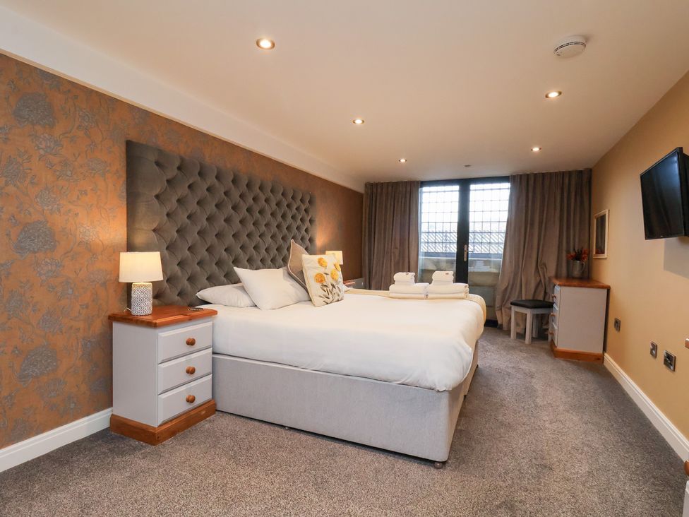 A bedroom with a bed, nightstand, and television at Olton Hall @ Engine Shed Whitby