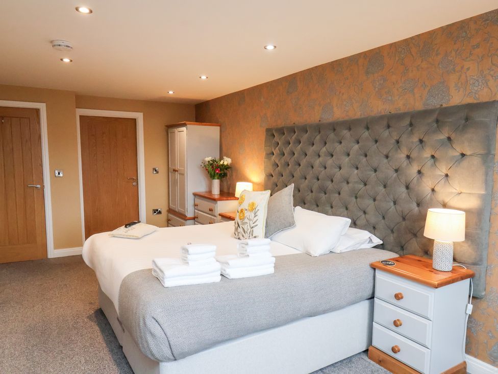 A bedroom with a bed, nightstand, and flowers at Mallard @ Engine Shed in Whitby