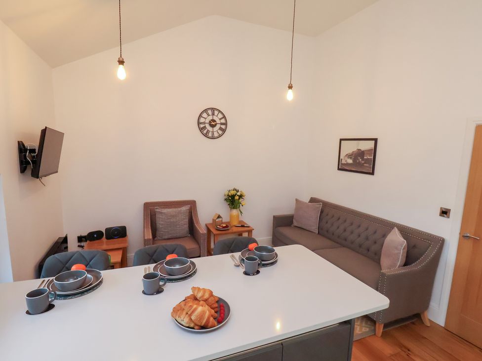 A living room with a table, couch, and television at Evening Star @ Engine Shed in Whitby