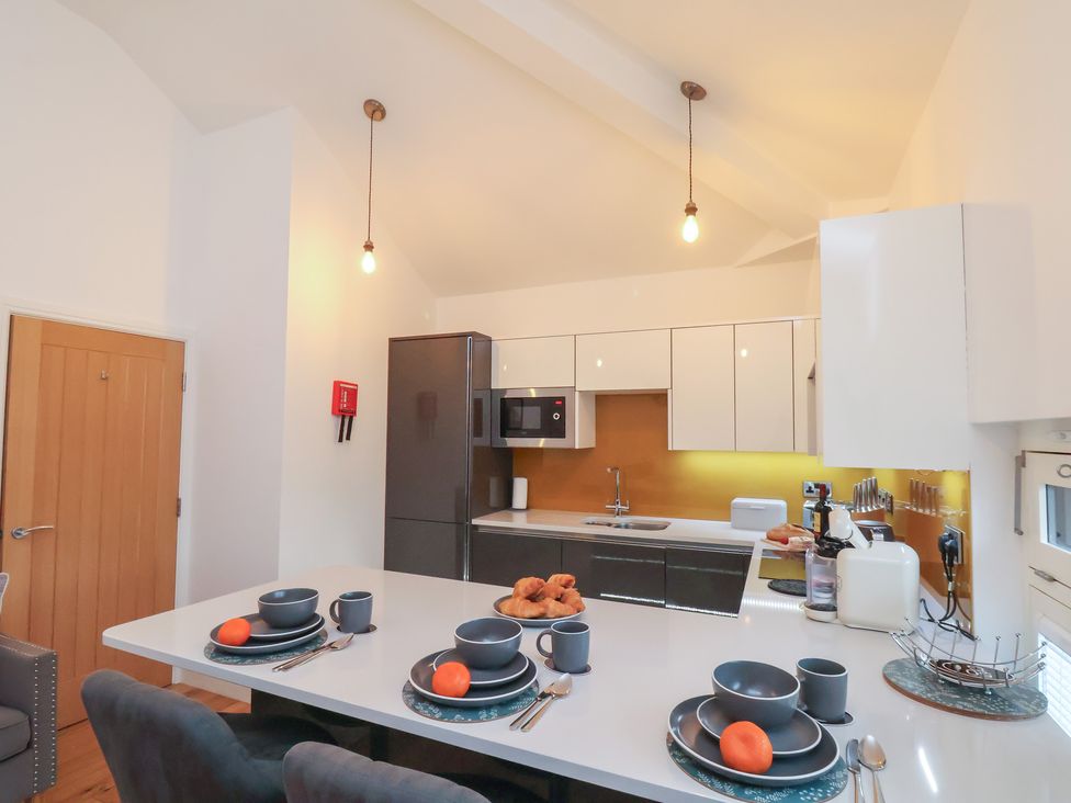 A kitchen with dining table and appliances at Evening Star @ Engine Shed in Whitby