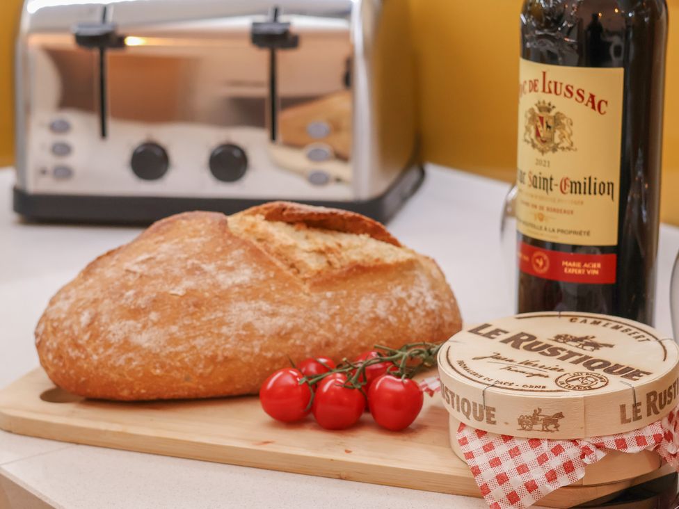 A kitchen countertop with bread, cheese, tomatoes, and a wine bottle at Evening Star @ Engine Shed in Whitby