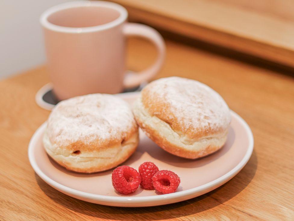A plate with doughnuts and raspberries next to a cup at George Stephenson @ Engine Shed in Whitby