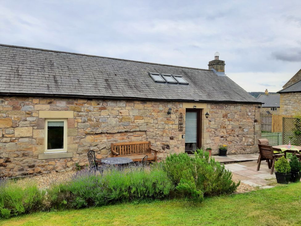 An outdoor area with seating and plants at Hemmel Cottage in Chatton