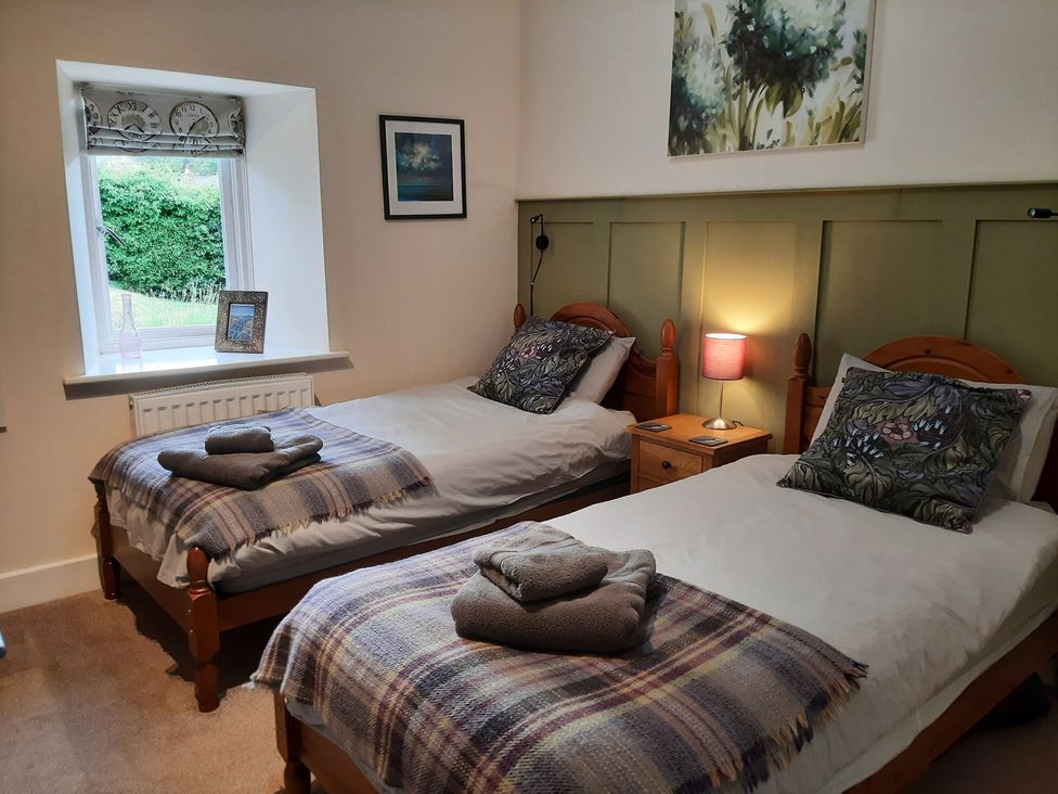 A bedroom with two single beds and a window at Hemmel Cottage in Chatton