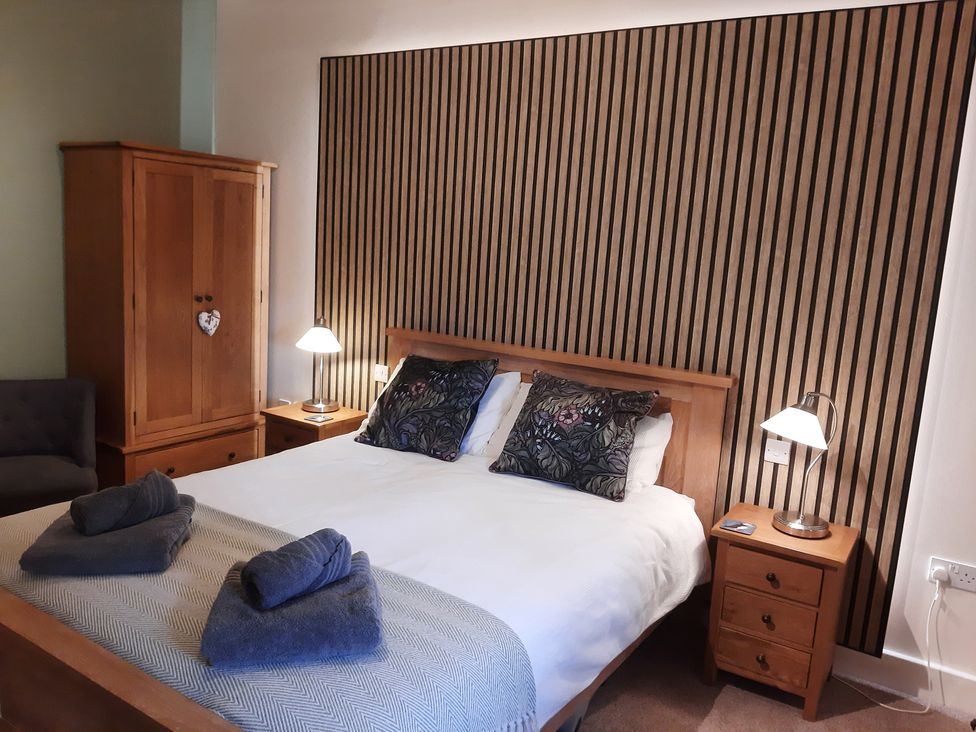 A bedroom with a bed and wooden furniture at Hemmel Cottage in Chatton
