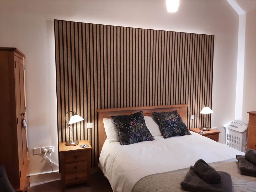 A bedroom with a bed and wardrobe at Hemmel Cottage in Chatton