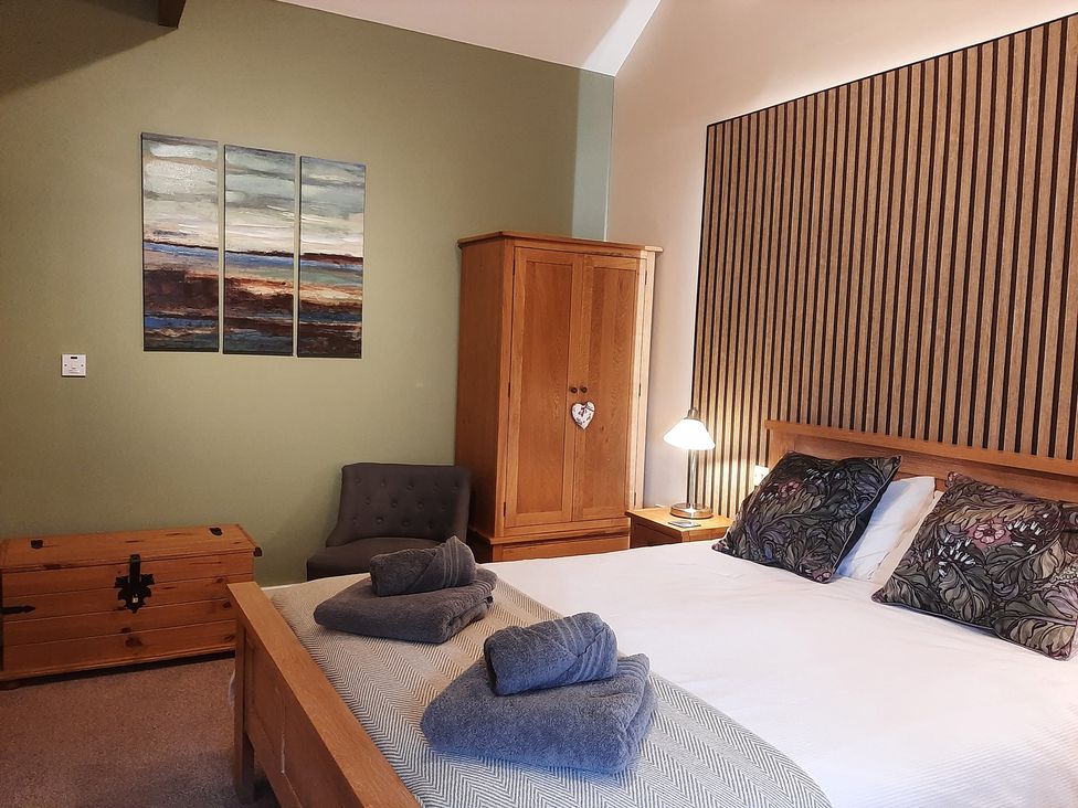 A bedroom with a bed and a wardrobe at Hemmel Cottage in Chatton