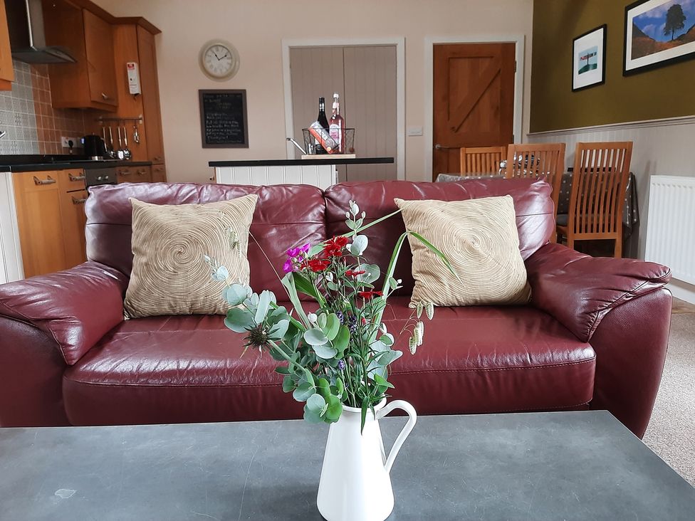 A living room with a sofa and flower vase at Hemmel Cottage in Chatton
