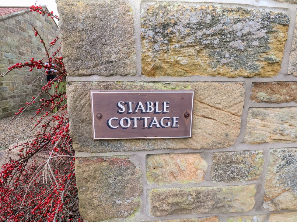 A sign on a stone wall at Stable Cottage in Robin Hoods Bay