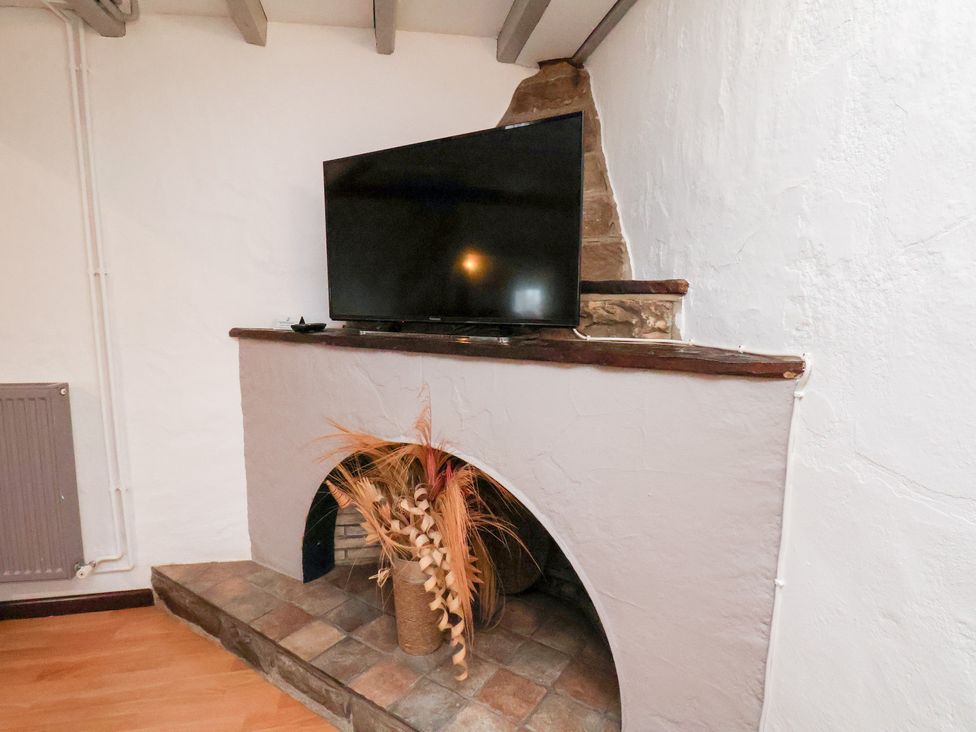 A living room with a television above a fireplace at Stable Cottage in Robin Hoods Bay