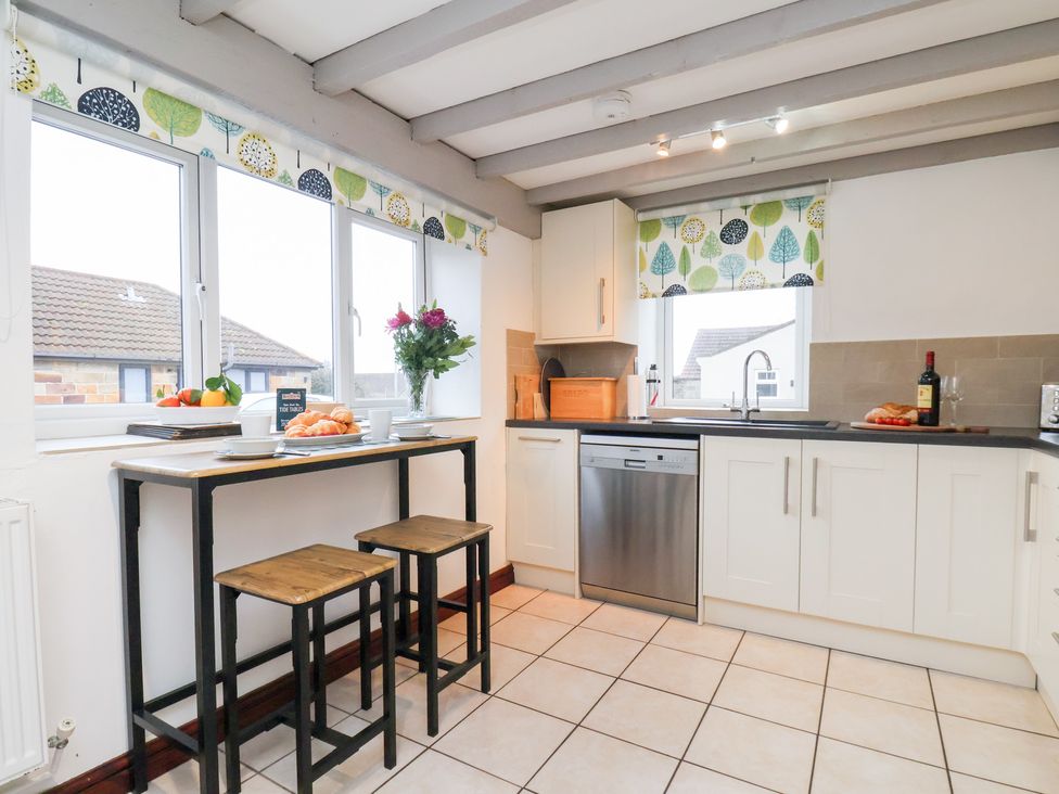 A kitchen with a table and stools at Stable Cottage in Robin Hoods Bay