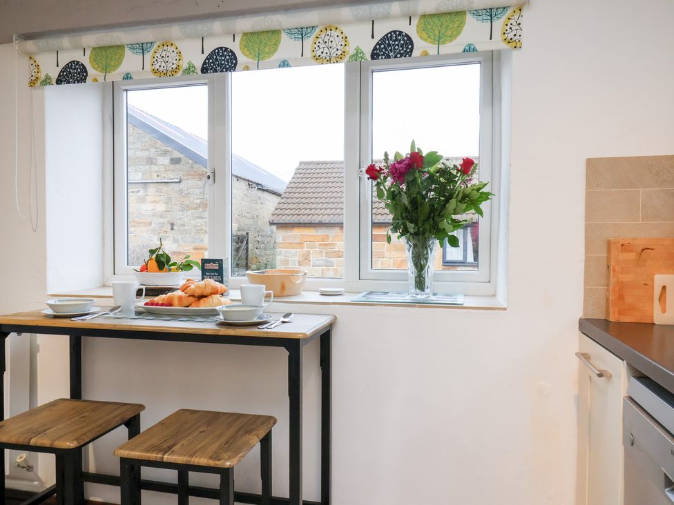 A kitchen with a table set for breakfast and flowers at Stable Cottage in Robin Hoods Bay