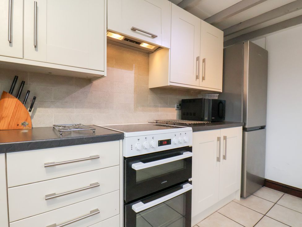 A kitchen with cabinets, oven, microwave, and refrigerator at Stable Cottage in Robin Hoods Bay