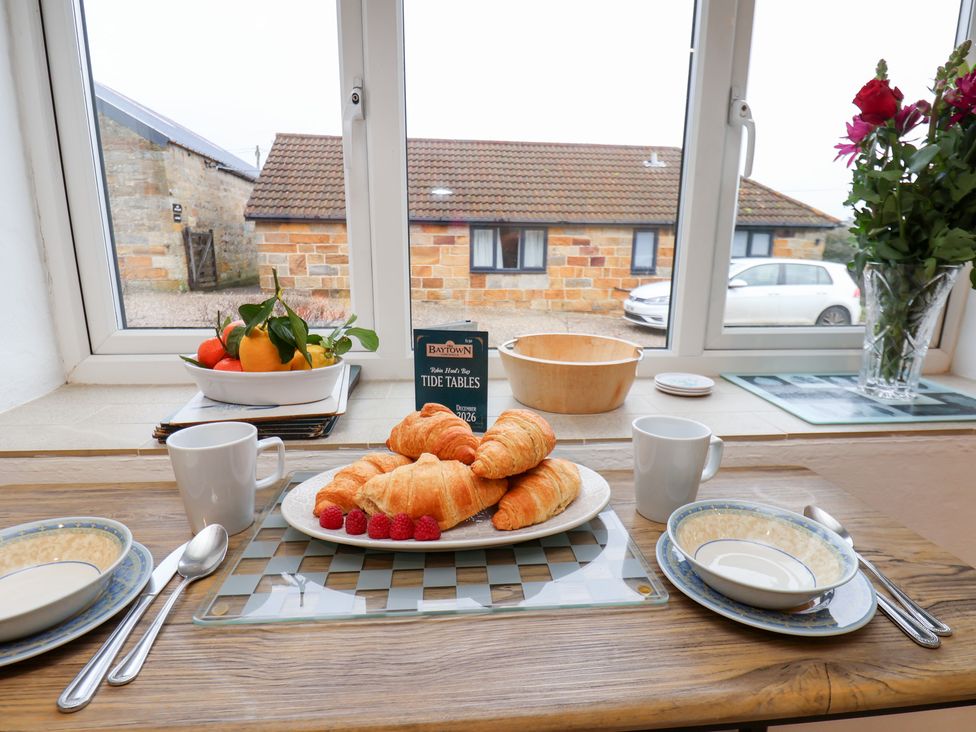 A dining room with breakfast items including croissants and fruit at Stable Cottage in Robin Hoods Bay