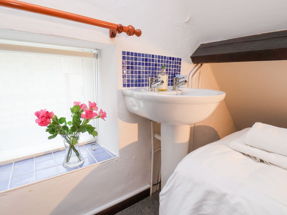 A bathroom with a wash basin and flowers at Stable Cottage in Robin Hoods Bay