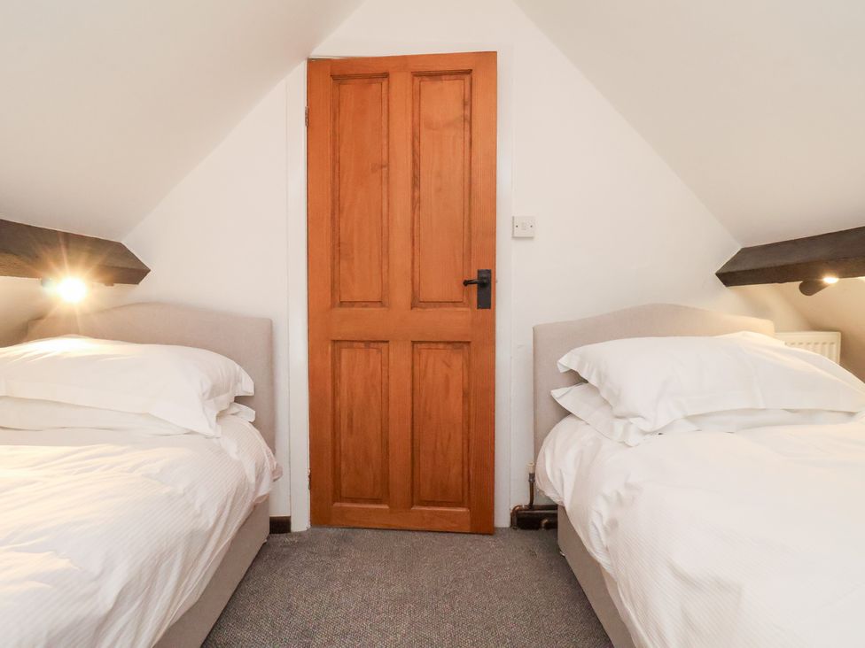 Two single beds in a bedroom with a wooden door at Stable Cottage in Robin Hoods Bay
