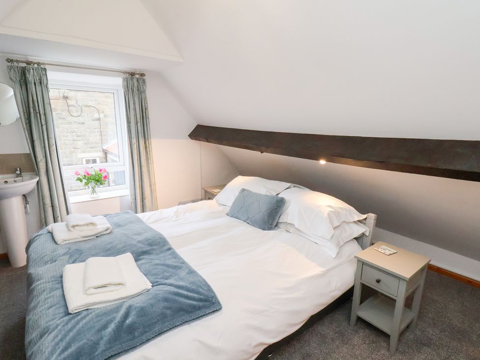 A bedroom with a bed and window at Stable Cottage in Robin Hoods Bay