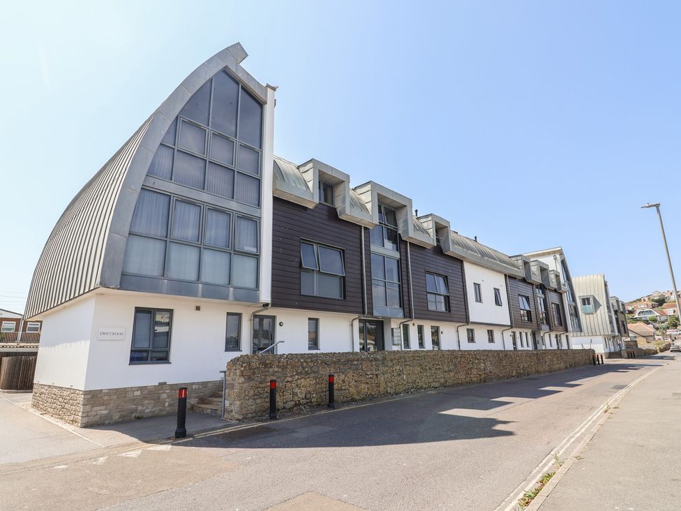 A building with large windows and stone wall at Harbourwalk in West Bay