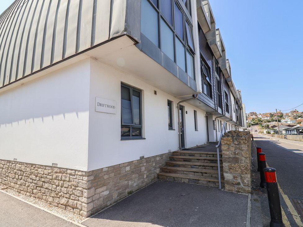 A building exterior with a sign and steps at Driftwood in West Bay