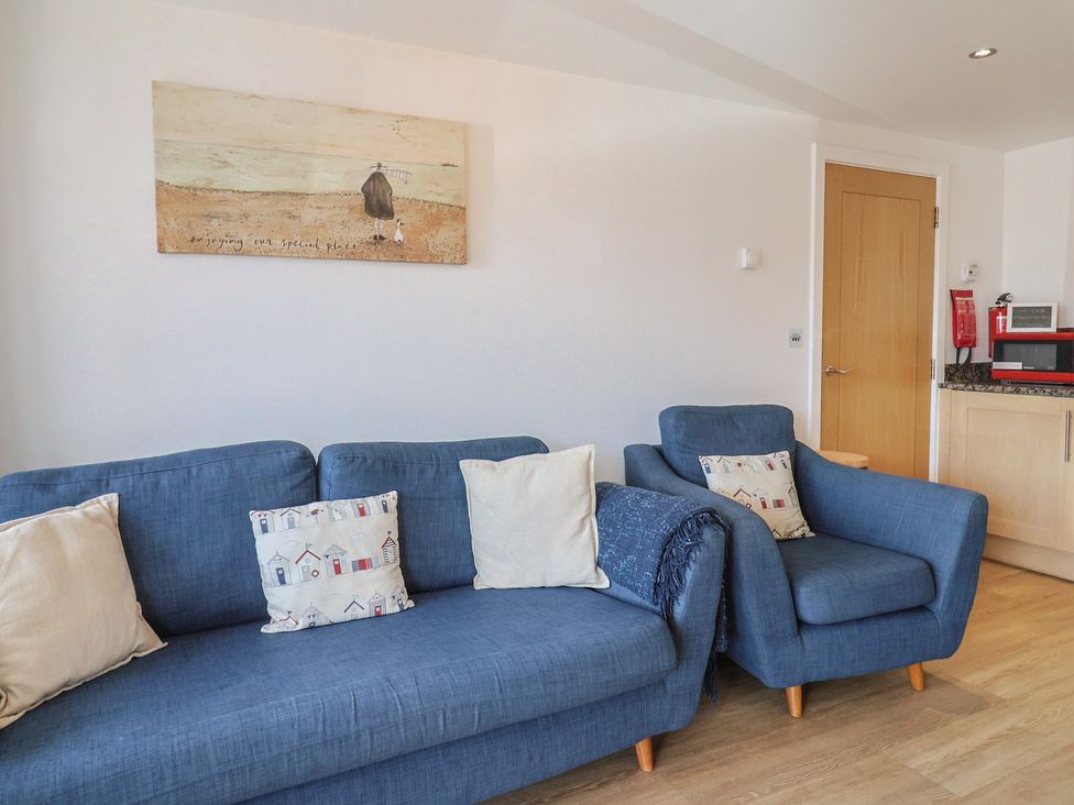 A living room with a blue sofa and armchair at Harbourwalk in West Bay