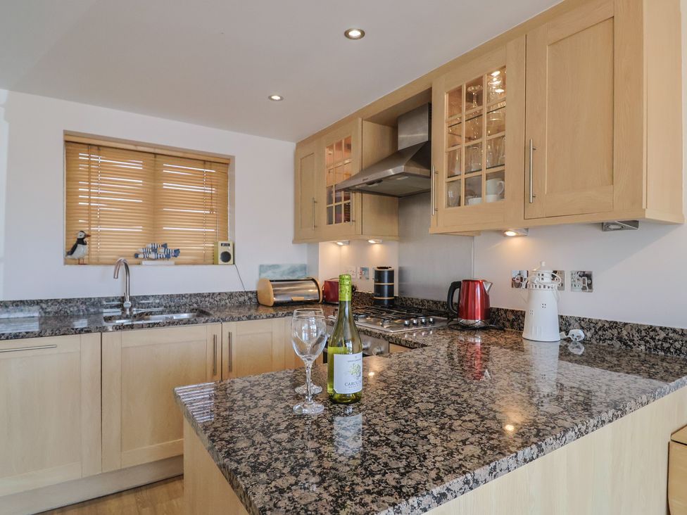 A kitchen with a granite countertop and cabinets at Harbourwalk in West Bay