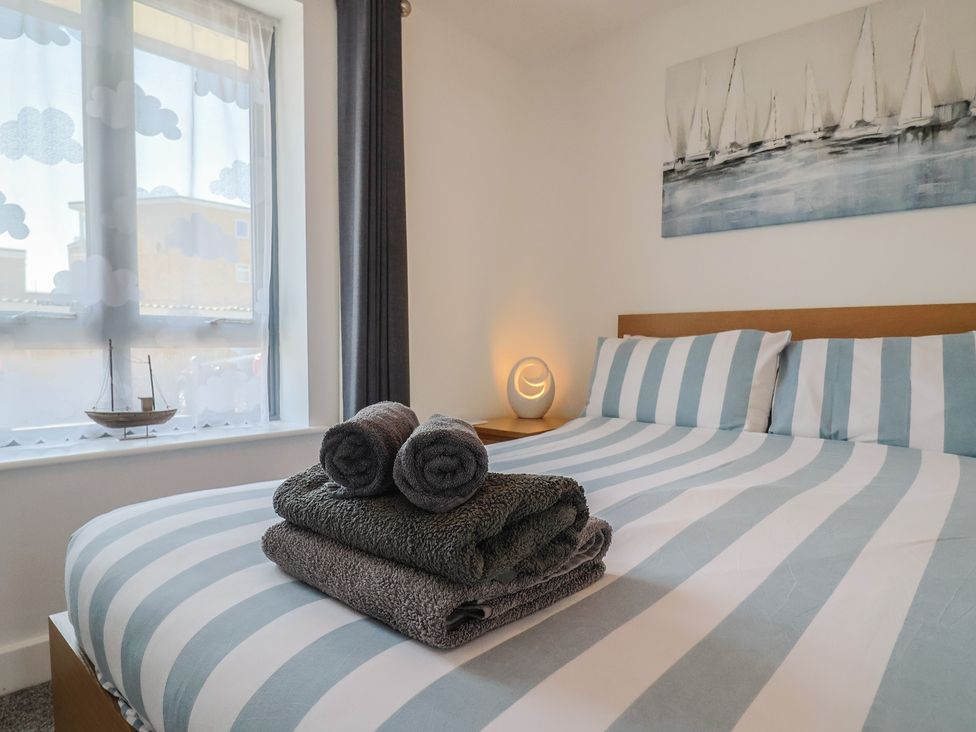 A bedroom with a bed and towels on top at Harbourwalk in West Bay