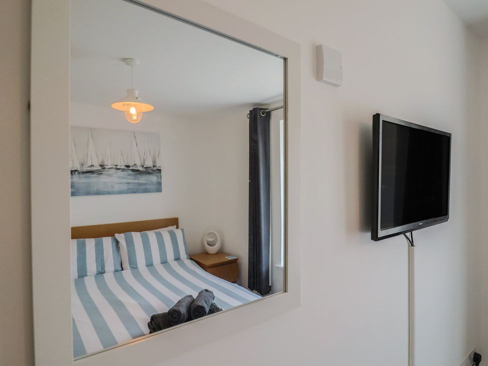 A bedroom with a bed and television at Harbourwalk in West Bay