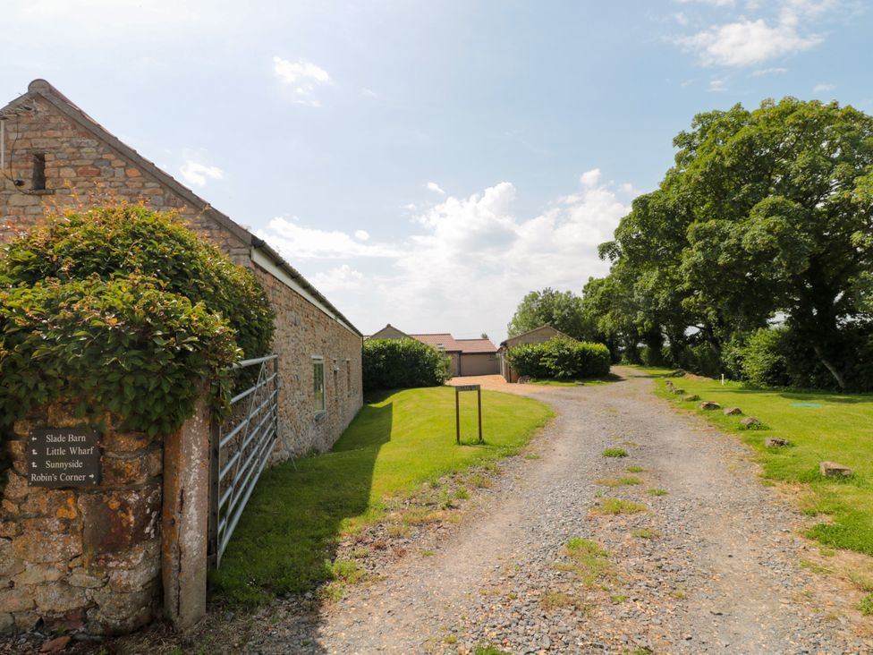 Exterior view of a stone building and gravel road at Robins Corner in Bleadon