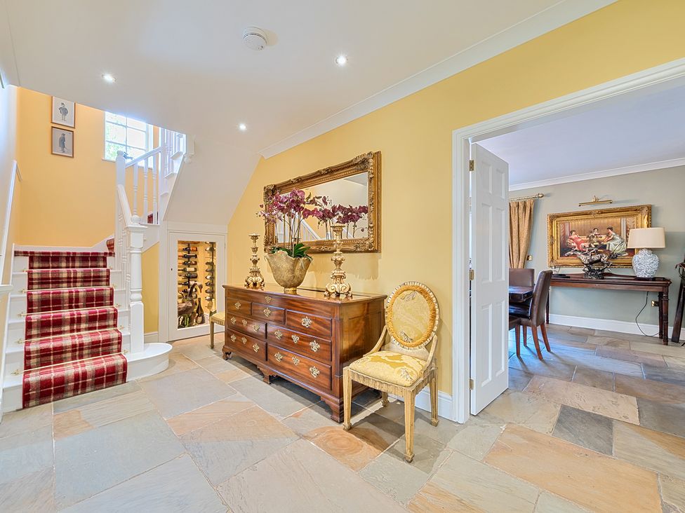 A hallway with a staircase and a table with a mirror at Moor End Manor in Stalmine