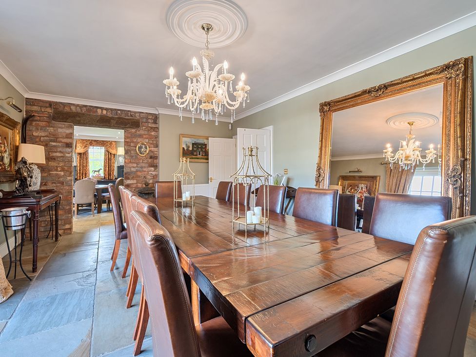 A dining room with a large table and chandelier at Moor End Manor in Stalmine
