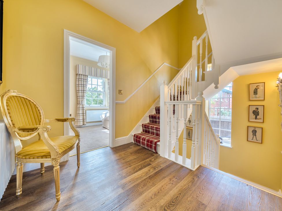 A hallway with a staircase and a chair at Moor End Manor in Stalmine