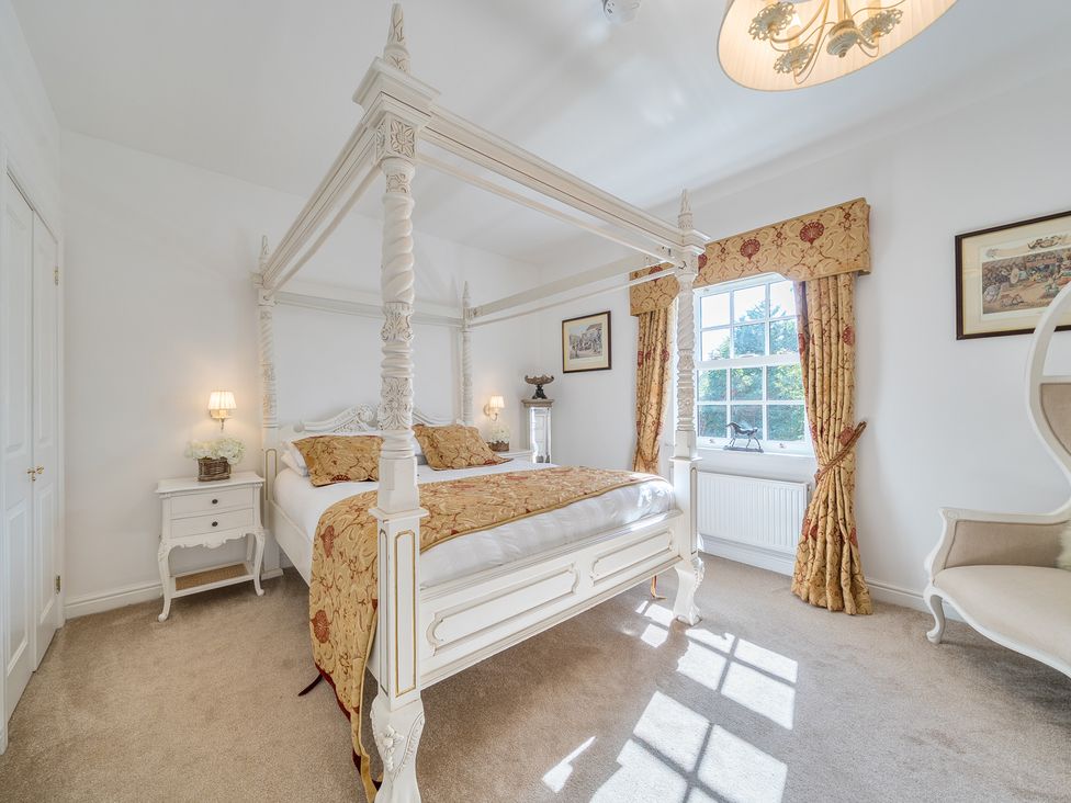 A bedroom with a four-poster bed and window at Moor End Manor in Stalmine