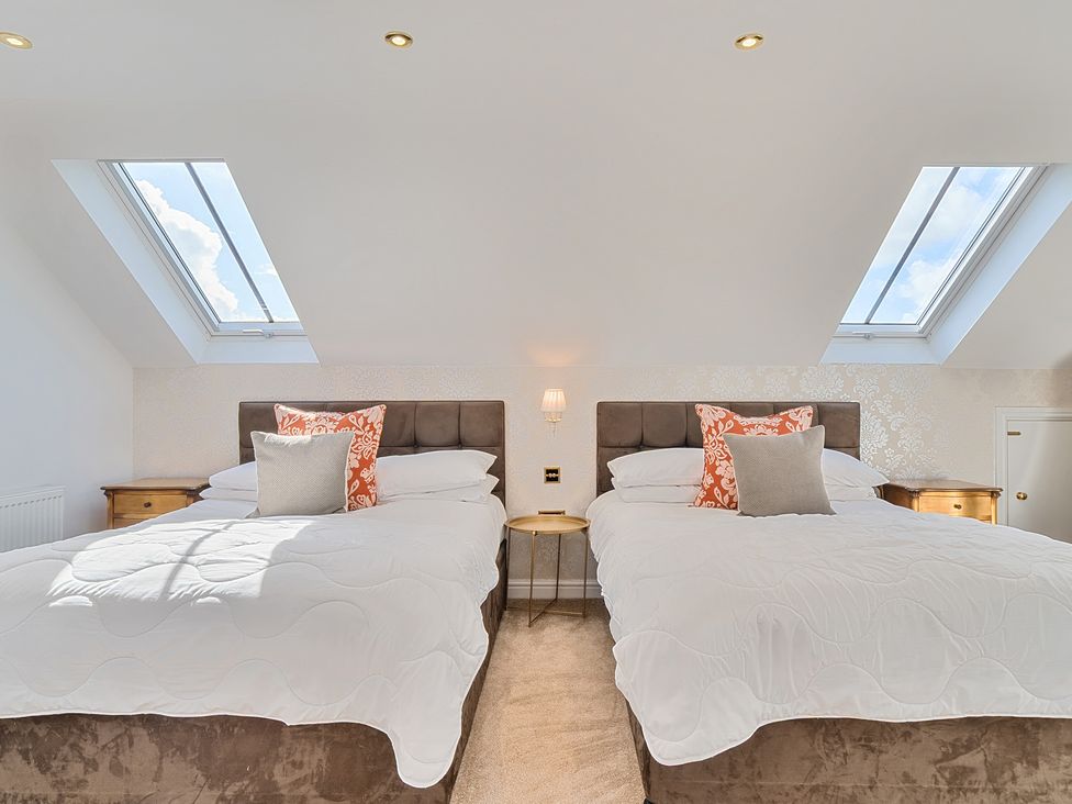 A bedroom with two beds and windows at Moor End Manor in Stalmine