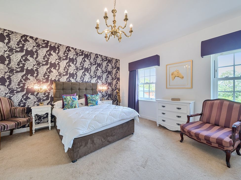 A bedroom with a bed and armchairs at Moor End Manor in Stalmine