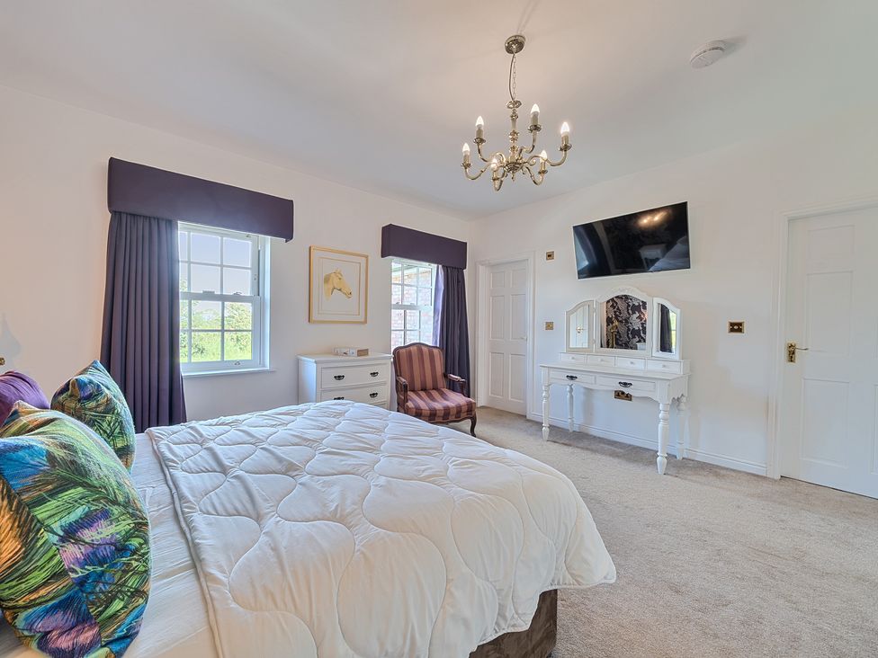 A bedroom with bed, tv, and vanity at Moor End Manor in Stalmine