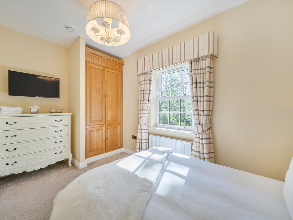 A bedroom with a bed, dresser, and television at Moor End Manor in Stalmine