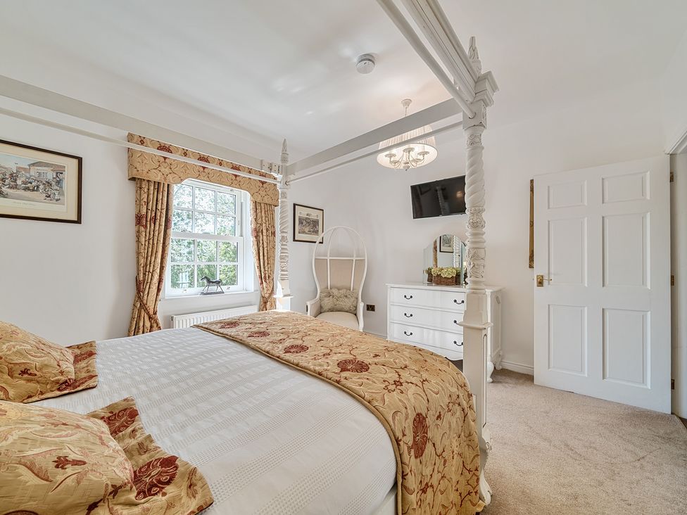 A bedroom with a bed, dressing table, and television at Moor End Manor in Stalmine